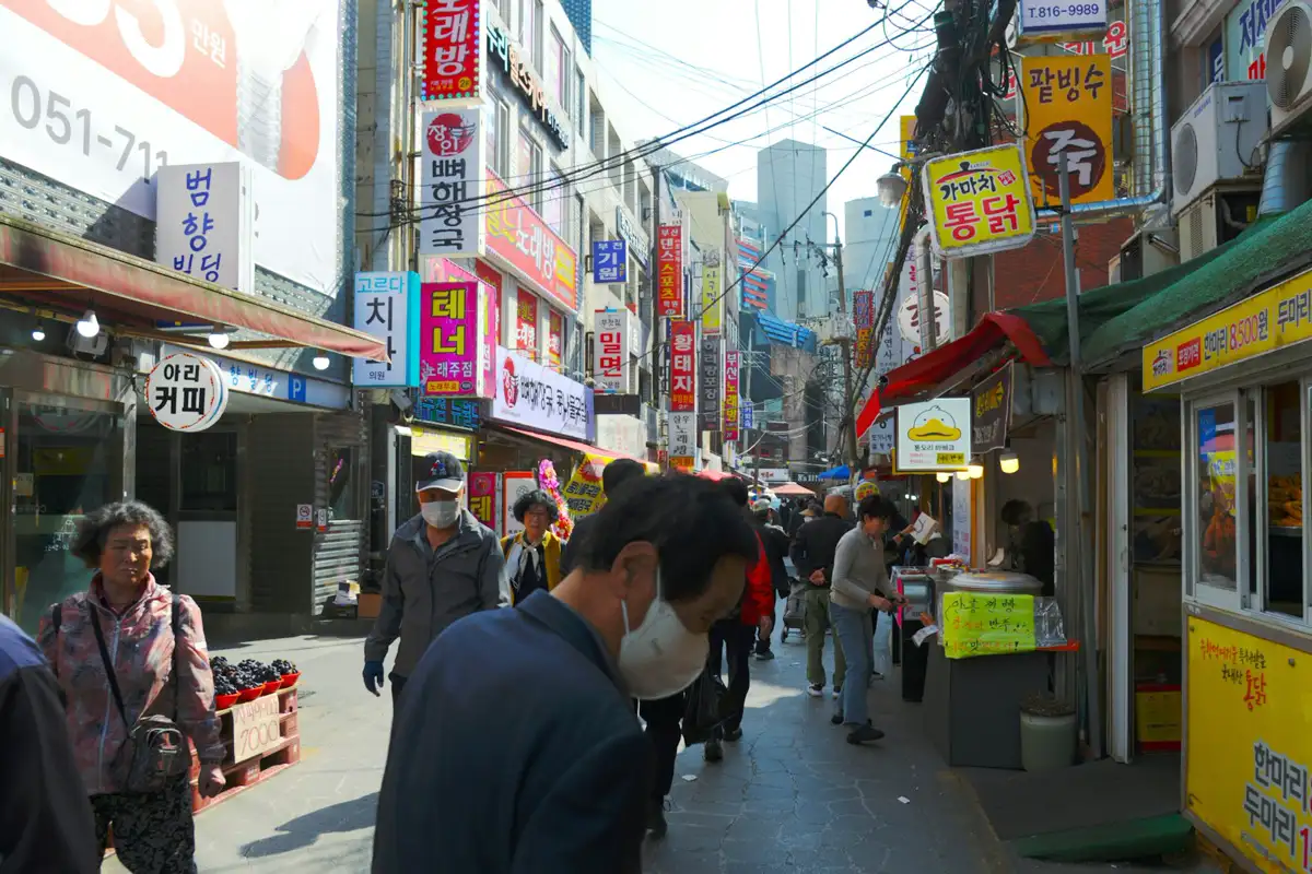 부산 상점가 골목을 걷는 사람들과 한글 간판