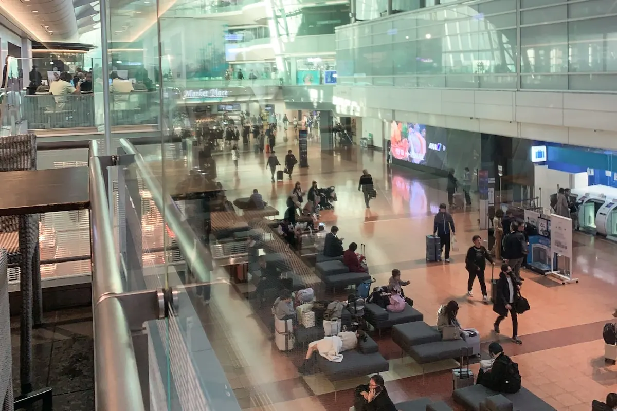 하네다공항 터미널 1 안에서 수하물을 든 여행자들이 이동하는 모습