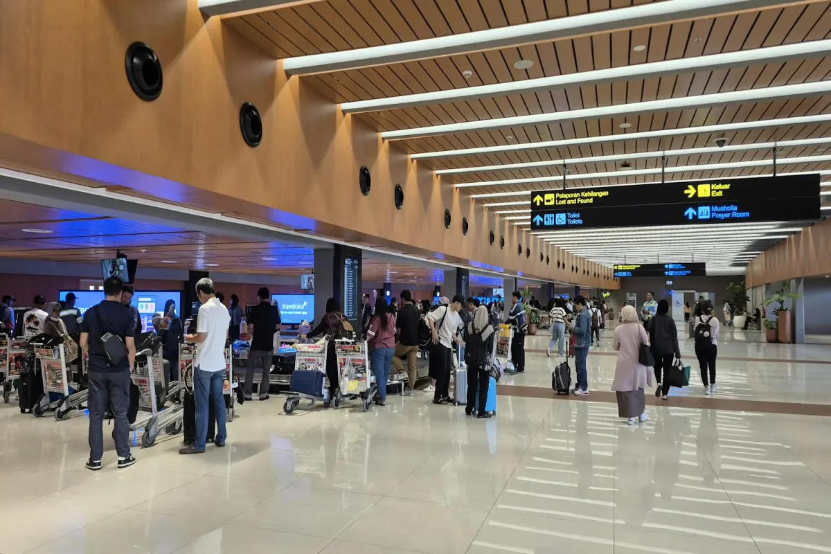 수하물을 든 사람들이 공항 터미널 통로를 걷는 모습