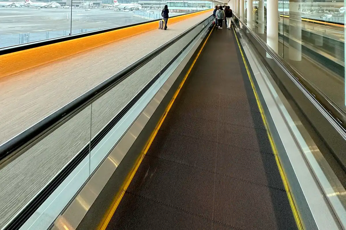 나리타공항 긴 실내 보행로를 지나가는 여행자
